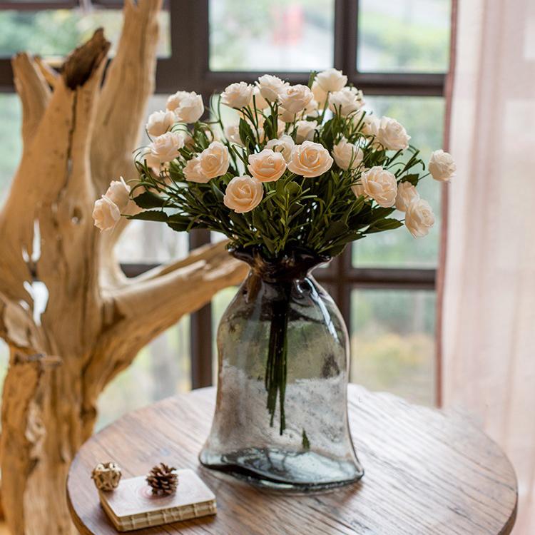 Bouquet of white flowers in a clear glass vase on a wooden table.
