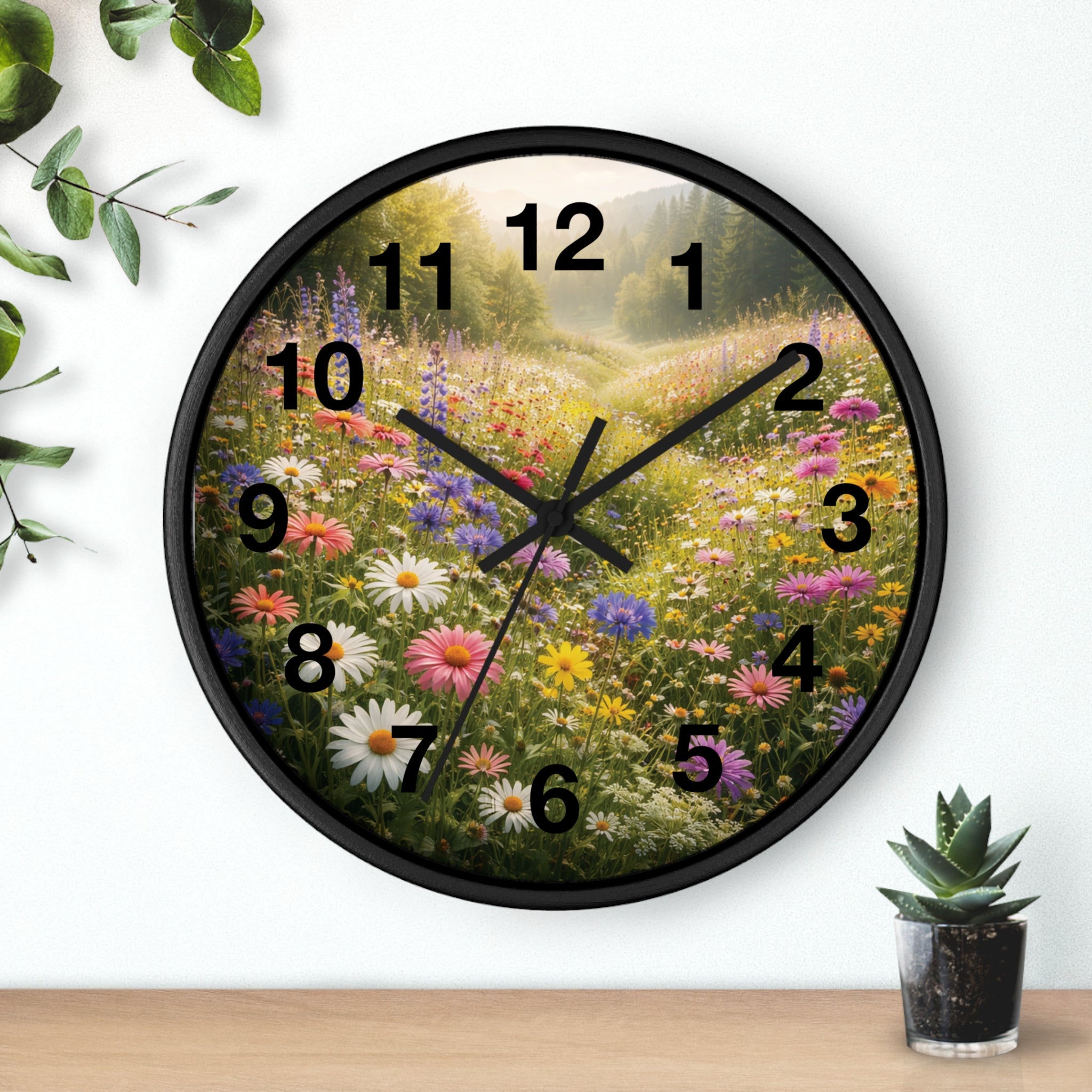 Wall clock with floral design on a white wall with a plant and pot below.