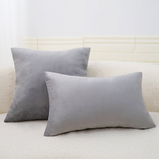 Two gray pillows on a light-colored sofa with a neutral wall background