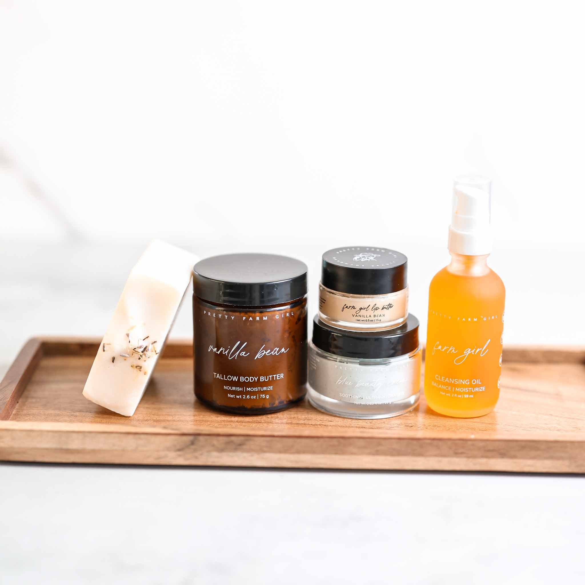 Collection of skincare products including jars and a bottle on a wooden tray with a white background.