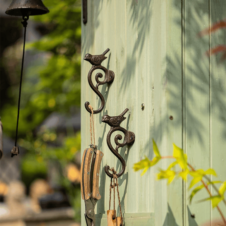 Decorative metal hook with birds on a wooden door with blurred greenery in the background