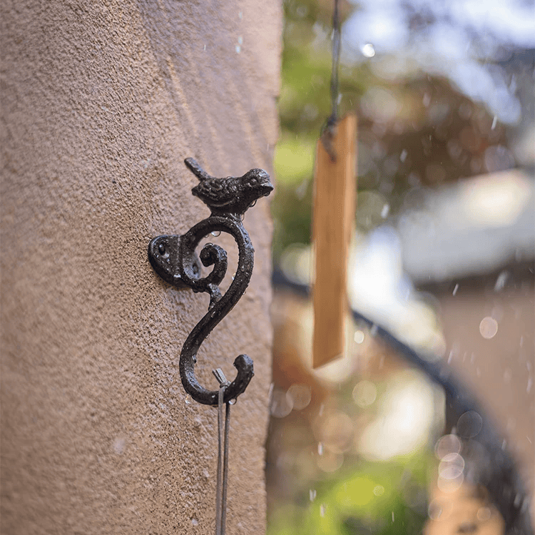 Decorative metal hook on a textured wall with blurred outdoor background