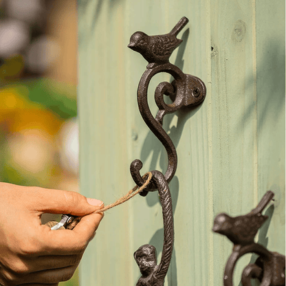 Decorative metal hook with bird design on a wooden surface