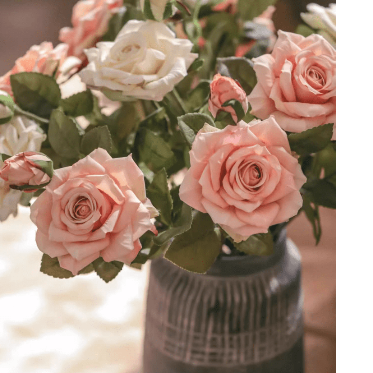 Bouquet of pink and white roses in a textured vase with a blurred background