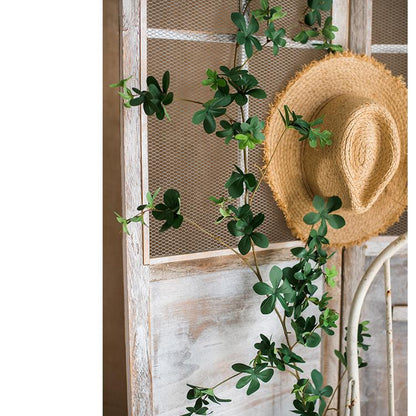 Straw hat with green leaves against a wooden panel background