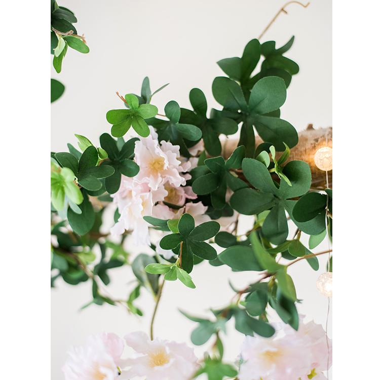 Decorative wreath with green leaves and pink flowers on a white background