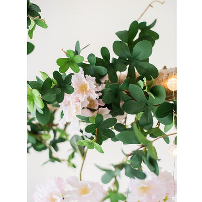 Decorative wreath with green leaves and pink flowers on a white background