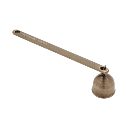 Bronze candle snuffer with 'The Woodwick Candle Co.' branding on a white background