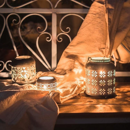 Decorative lanterns with intricate patterns on a wooden surface, casting a warm glow.