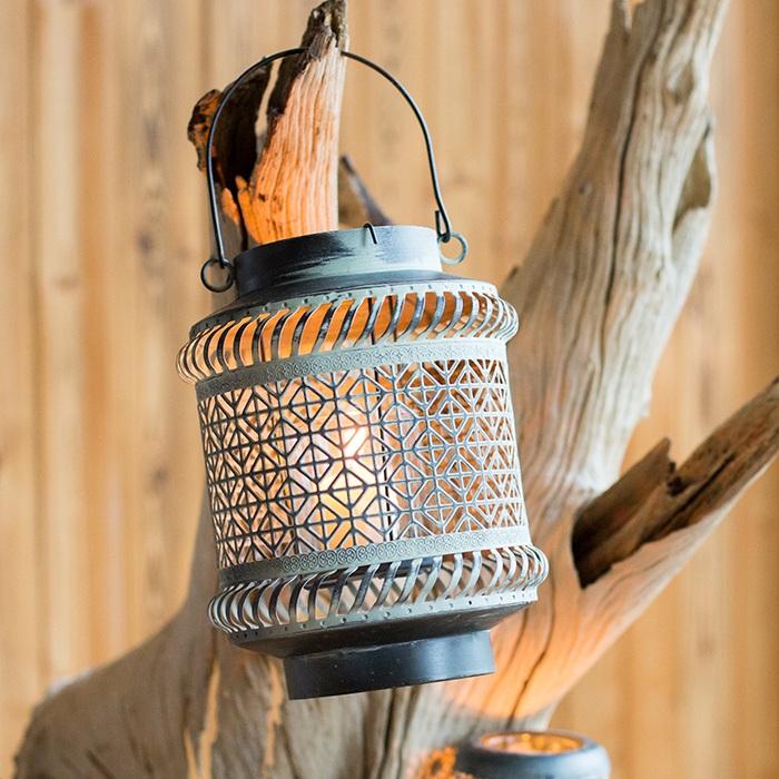 Decorative lantern with geometric pattern hanging on a wooden branch